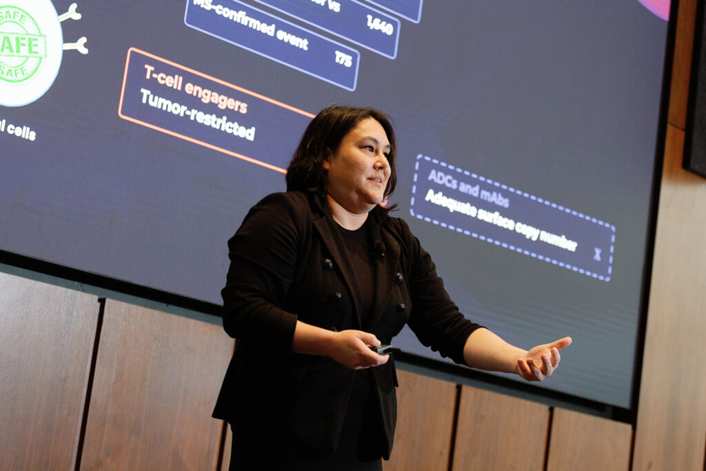 A speaker presents on stage in front of a slide about T-cell engagers.