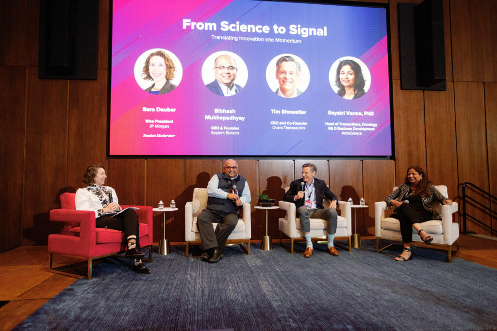 Moderator and panelists on stage during the From Science to Signal panel, with the session title on the screen behind them.